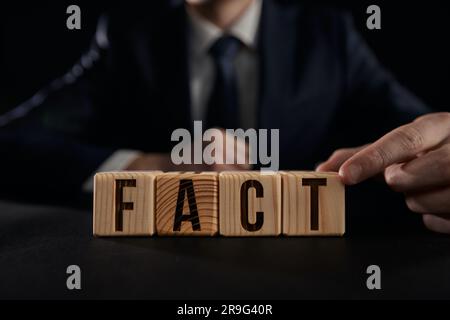 Mano maschile che mostra fatti su un cubo di legno. Foto Stock