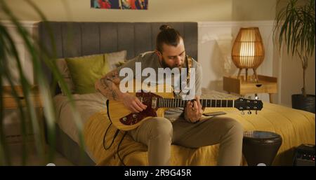 L'uomo suona la chitarra in camera da letto. Foto Stock