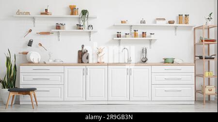 Interno di cucina luminosa con banconi bianchi e utensili Foto Stock