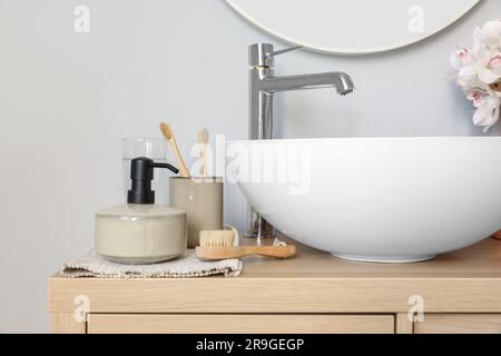 Lavandino e accessori da bagno su mobile in legno in bagno Foto Stock