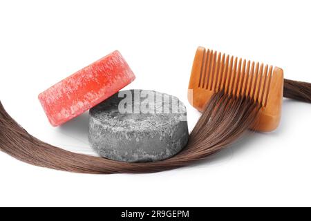 Shampoo colorato e solido con capelli e pettine su sfondo bianco Foto Stock