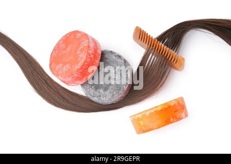 Shampoo colorato e solido con capelli e pettine su sfondo bianco Foto Stock