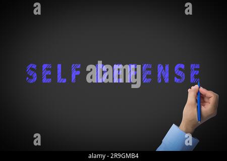 Uomo che scrive parole autodifesa su sfondo nero, primo piano Foto Stock