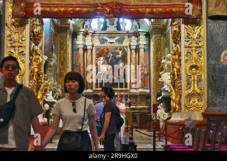 Una coppia sfocata di turisti asiatici esce dalla Cappella della Langue di Aragona all'interno di St Co-cattedrale di Giovanni a la Valletta, Malta Foto Stock