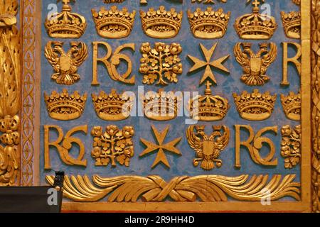 Dettagli decorativi dorati con croce maltese, monogramma 'RC' e altri simboli sulla parete all'interno di St Co-cattedrale di Giovanni a la Valletta, Malta Foto Stock