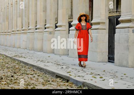 Passeggia attraverso il Palais Royal indossando un abito contadino ricamato rosso, una donna asiatica matura e glamour a Parigi Foto Stock