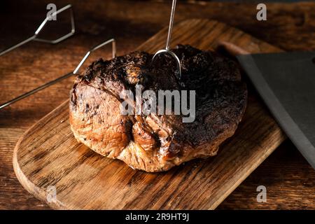 Un pezzo di carne cotto al forno. Un pezzo di maiale in spezie cotto nel forno su un asse di legno. Foto Stock