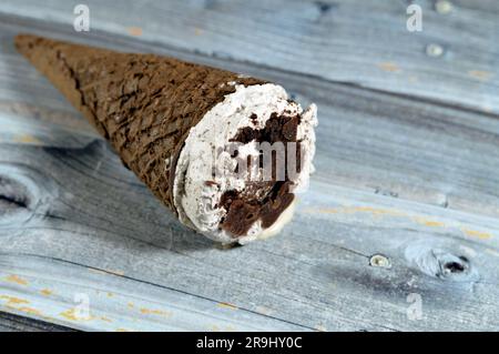 Gelato di cioccolato al cacao e cono alla vaniglia con condimento di biscotti con gocce di cioccolato in coni di wafer croccanti, sciogliendo il gelato freddo Foto Stock