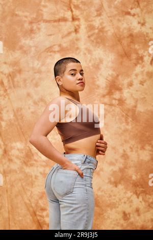 denim fashion, gen z, giovane donna curvy in posa su sfondo beige macchiato, forme diverse, movimento di positività corporea, autostima, fiducia in se stessa, breve Foto Stock