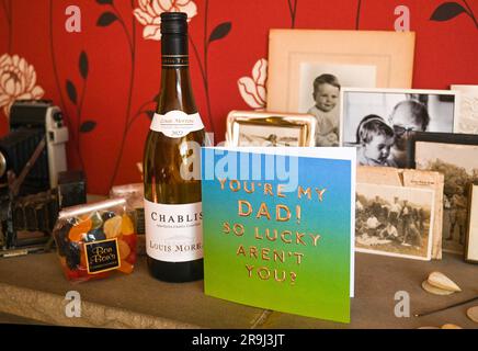 Tessera per il giorno del papà e regali di vino Chablis e gomme da vino in mostra con alcune vecchie fotografie di famiglia Foto Stock