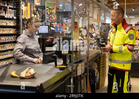 27 giugno 2023, Assia, Brachttal: Un medico di emergenza si trova in un negozio di supermercato (scena posta). La campagna "corsia di emergenza al checkout" nel distretto di Mainz-Kinzig ha lo scopo di accelerare l'elaborazione dei servizi di emergenza al checkout in futuro. Foto: Tim Würz/dpa Foto Stock