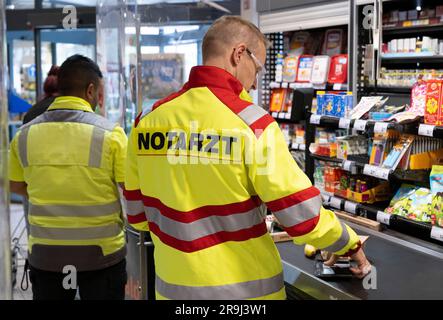 27 giugno 2023, Assia, Brachttal: Un medico di emergenza si trova in un negozio di supermercato (scena posta). La campagna "corsia di emergenza al checkout" nel distretto di Main-Kinzig ha lo scopo di accelerare l'elaborazione dei servizi di emergenza al checkout in futuro. Foto: Boris Roessler/dpa Foto Stock