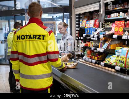 27 giugno 2023, Assia, Brachttal: Un medico di emergenza si trova in un negozio di supermercato (scena posta). La campagna "corsia di emergenza al checkout" nel distretto di Main-Kinzig ha lo scopo di accelerare l'elaborazione dei servizi di emergenza al checkout in futuro. Foto: Boris Roessler/dpa Foto Stock