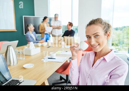 Ritratto di una donna d'affari sorridente che beve caffè in ufficio Foto Stock