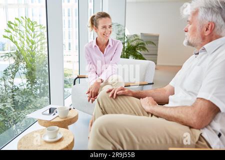 Donna d'affari sorridente che guarda un uomo d'affari anziano sicuro di sé nella sala Foto Stock
