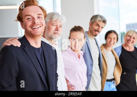 Colleghi d'affari sorridenti, uomini e donne, che si trovano fianco a fianco Foto Stock