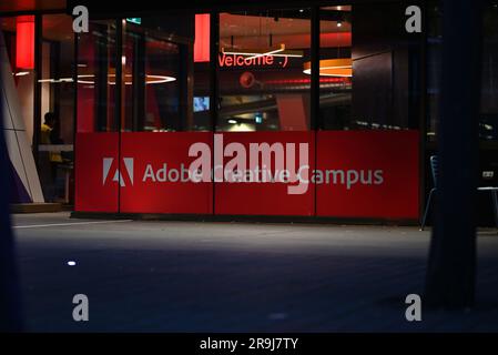 Insegna Adobe Creative Campus rossa e bianca alla RMIT University, in una finestra vicino a un ingresso, illuminata durante la notte Foto Stock