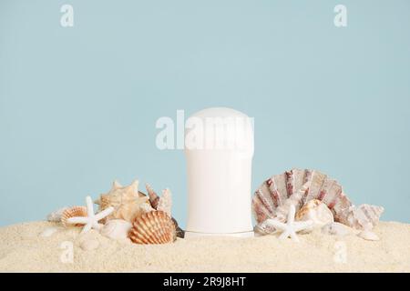 Bianco antiperspirante, deodorante e conchiglie sulla sabbia su sfondo blu. Concetto di prodotti da bagno di mare e cosmetici estivi biologici. Carrozzina Foto Stock