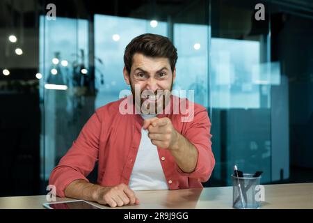 Uomo arrabbiato e aggressivo che parla in videochiamata, capo in camicia che guarda la webcam seduto in ufficio sul posto di lavoro, riunione online pov Foto Stock