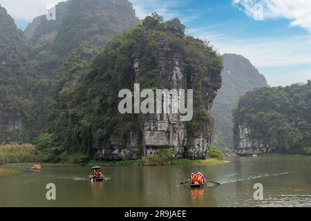 Ninh Binh, Vietnam-Aprile 2023; Vista di barche a remi sampan con turisti in tour grotta sul Delta del Fiume Rosso nel paesaggio di Trang An tra li boschivi Foto Stock