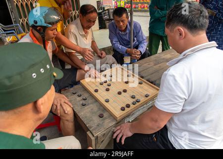 BAC ha, Vietnam-aprile 2023; vista ad alto angolo di due uomini che giocano a Xiangqi, chiamati anche scacchi cinesi o scacchi di elefanti mentre sono osservati da diversi oth Foto Stock