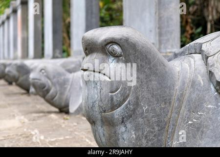 Ninh Binh, Vietnam - marzo 2023; vista ravvicinata di una linea di tartarughe di pietra vicino al Palazzo Vu Lam nel delta del fiume Rosso circondato da rocce calcaree boscose Foto Stock