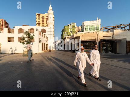 Gedda, Arabia Saudita - due uomini vestiti con abiti tradizionali camminano davanti alla moschea al Ma'amar nella città vecchia di Gedda, al-Balad, in Arabia Saudita Foto Stock