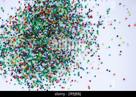 Piccole perle multicolore su sfondo bianco. Foto Stock