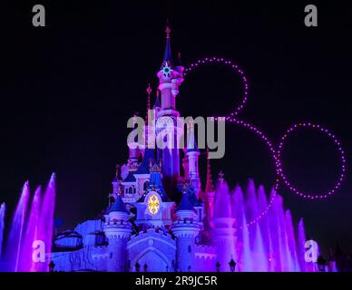 Parigi, Francia - 2 giugno 2023: Castello illuminato per lo spettacolo del 30° anniversario al Disneyland Paris Park. I droni disegnano i trenta e la silhouette di Topolino nel cielo. Foto Stock