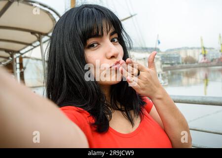 Ritratto selfie di giovane donna latina di etnia venezuelana vestita di rosso, con capelli neri, sorridente felice all'aperto, turista nella città di Buenos ai Foto Stock