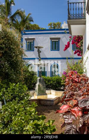 Precioso Rincón en el Puerto de Mogán con sus casas blancas con los marcos de puertas y ventanas pintados de vivos colores. Múltiples buganvillas y ár Foto Stock