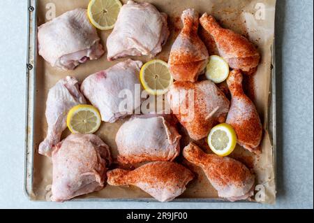 Cosce di pollo crude e cosce di rondine con e senza condimento su un vassoio da forno Primo piano con messa a fuoco selettiva Foto Stock