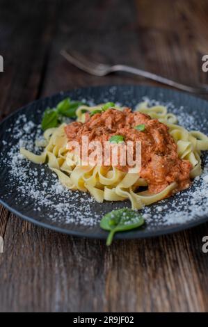 Tagliatelle con salsa di pomodoro al tonno e parmigiano grattugiato su un piatto Foto Stock