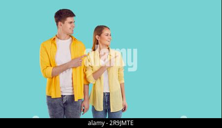 Giovane attraente uomo e donna caucasica che punta a lato sorridente guardando lo spazio delle copie Foto Stock