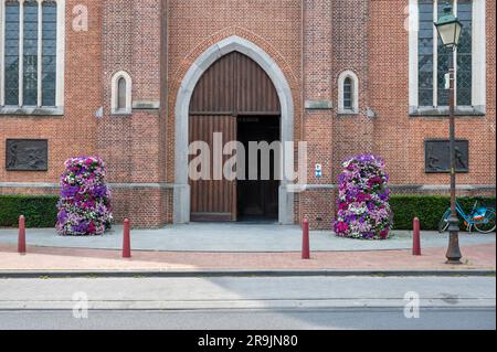 Wichelen, regione fiamminga orientale, Belgio, 16 giugno 2023 - facciata in mattoni e ingresso della chiesa di Saint Gertrude Foto Stock