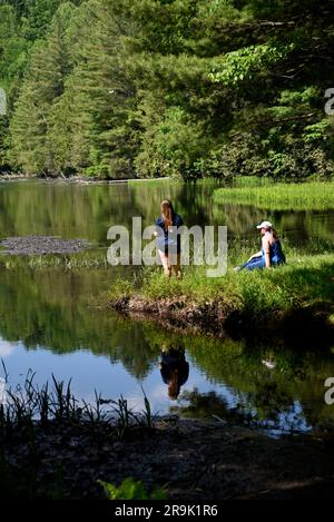 Una giovane ragazza pesca in un lago mentre sua madre guarda la Jefferson National Forest in Virginia USA. Foto Stock