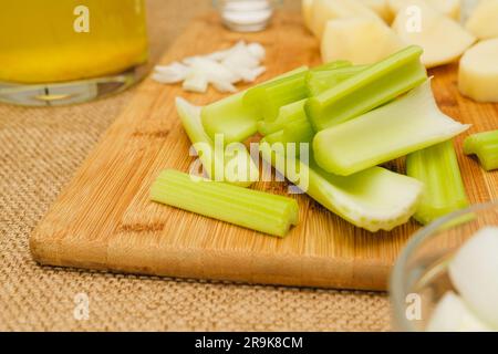 Verdure crude, come bastoncini di sedano, patate, cipolla tritata primo piano sul tavolo da cucina. Ingredienti per una ricetta di zuppa di sedano Foto Stock