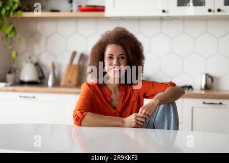 Bella giovane donna afro-americana in posa in un accogliente interno della cucina Foto Stock