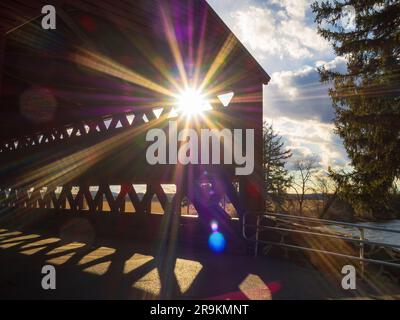 Una sunstar scoppia attraverso le lastre di legno del ponte coperto di Sachs in quercia rossa e pino, noto anche come il ponte coperto di Saucks e il Waterworks CoV Foto Stock