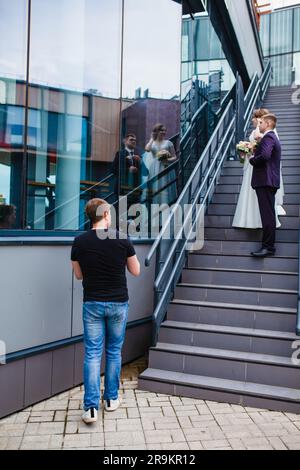 Un videografo professionista per matrimoni registra un film con gli sposi sulle scale Foto Stock