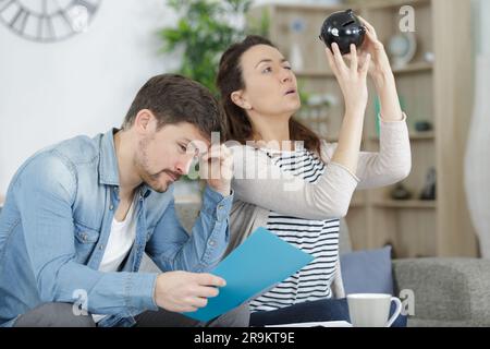 una coppia preoccupata che contava seduti su un divano Foto Stock