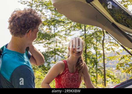 Due arrampicatori che scaricano la loro attrezzatura da una macchina, preparandosi a intraprendere la loro prossima avventura di arrampicata su roccia Foto Stock