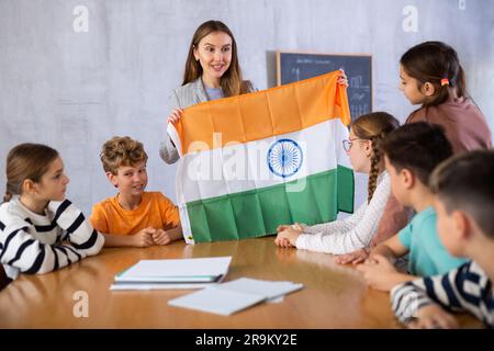 Insegnante femminile che lavora con studenti in classe scolastica, parlando della bandiera nazionale dell'India a lezione di storia Foto Stock