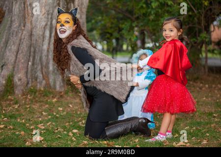 Bella giovane madre in costume da lupo che gioca con le sue figlie. Divertimento per tutta la famiglia con i costumi della storia del cappellino rosso in H Foto Stock