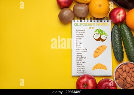 Informazioni sul raggruppamento dei prodotti sotto il loro indice glicemico in quaderni, frutta, verdura e mandorle su sfondo giallo, spianatura piatta. Spazio per Foto Stock