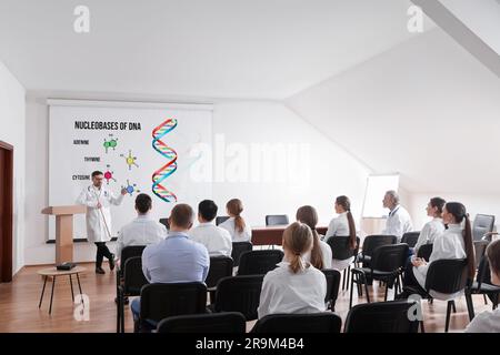 Professore che spiega le nucleobasi del DNA del pubblico durante la conferenza in sala conferenze. Schermo di proiezione con illustrazione Foto Stock