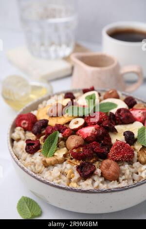 Farina d'avena con frutta liofilizzata, noci e menta su tavolo bianco Foto Stock