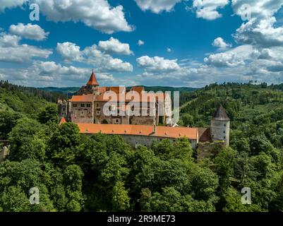 Vista aerea del castello di Pernstejn con il tetto rosso del palazzo gotico, torri rettangolari e rotonde, barbacane, piattaforma di cannoni in Moravia Foto Stock