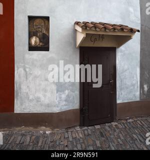 Vecchia porta di legno sul Vicolo d'Oro al Castello di Praga, Repubblica Ceca. Facciata storica di una piccola casa con porta intemprata, muro bianco, strada acciottolata e Foto Stock