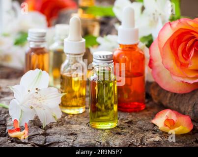 Bottiglie di oli aromatici essenziali e fiori freschi Foto Stock